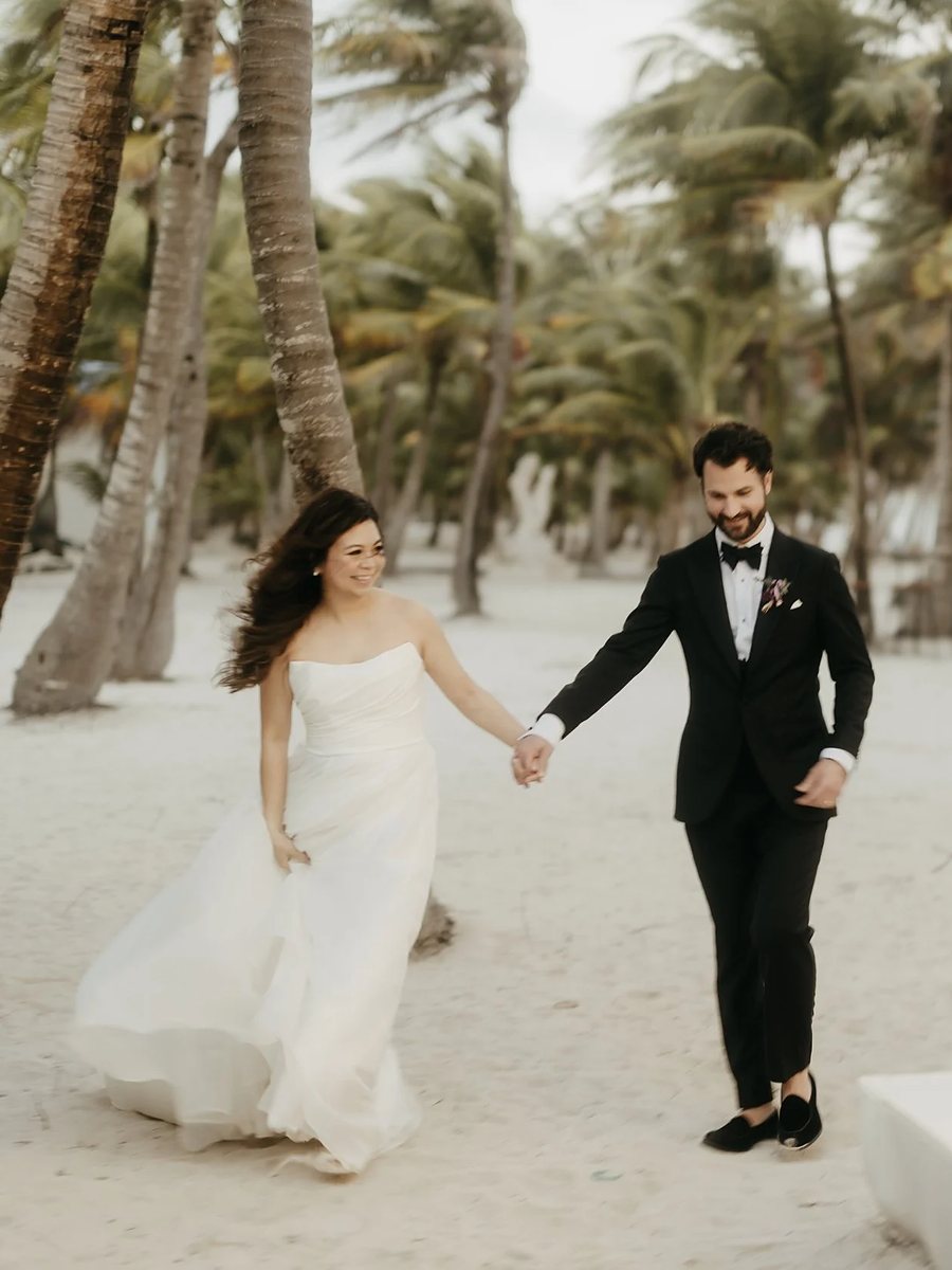 Bride and groom walking hand in hand on the beach in Tulum