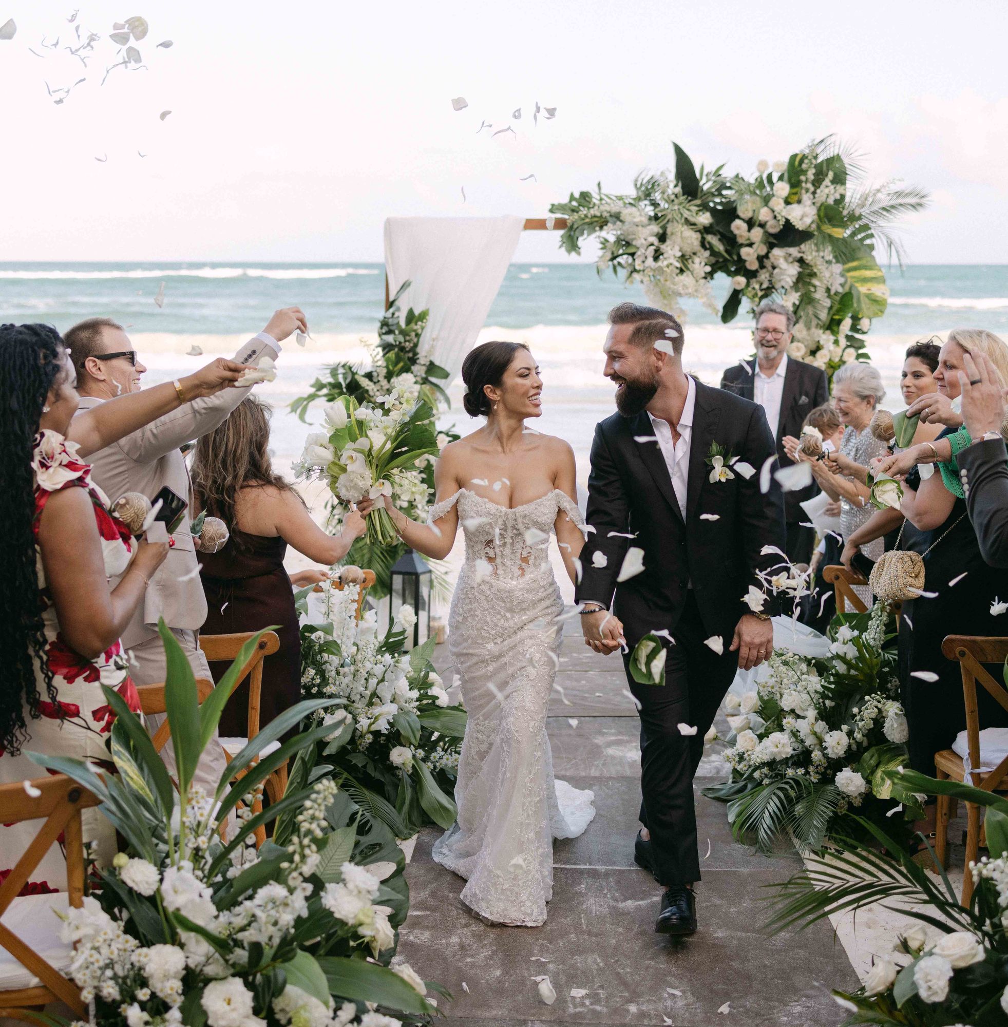 Newlyweds walking back down the aisle by the sea in Tulum